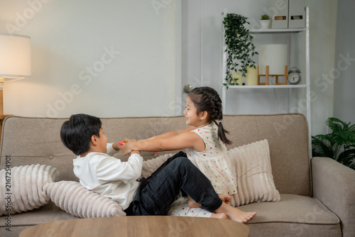 Cuadro en lienzo Children siblings playfully pulling toy on living room couch
