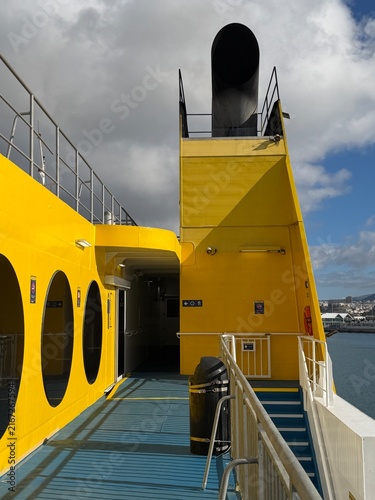 Canary Islands. View from a ferry captures various boats docked in a harbor with a city skyline and clouds, emphasizing the maritime environment and coastal landscape