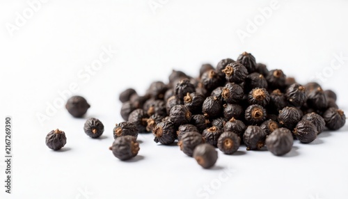 Black pepper closeup with scattered peppercorns on white background, whole black peppercorns showing textured surface and natural imperfections, black pepper in pile and single pieces,
