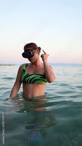 Vertical screen female diver demonstrates scuba hand signals for a problem then points to her ears to show strong pressures and explains how to equalize safely underwater