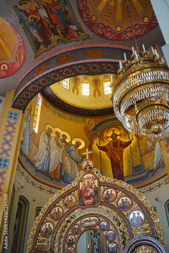 Картината върху платно Interior of a Christian church with frescoes, icons, a gilded iconostasis and large chandeliers beneath a high dome