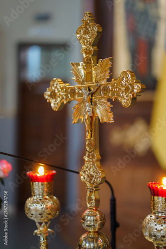 Photography Gilded cross with a figure of Christ stands between lit candles and features intricate ornamental church decoration