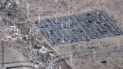 Heavy rainfall flood a stormwater drain on an urban road surface, slow motion