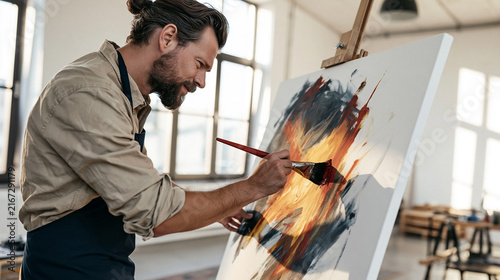 Male artist creating abstract painting on canvas in art studio, expressing creativity and inspiration