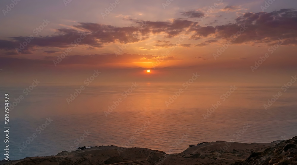 Obraz premium A serene sunset view over the tranquil ocean, featuring warm golden light and soft clouds above the horizon.