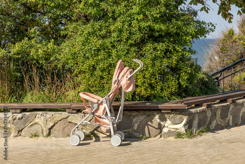 Obraz na płótnie Empty baby stroller beside wooden bench and green trees during daytime