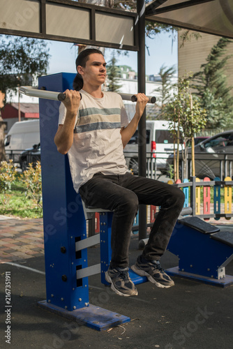 Fotografie A young man works out in an outdoor gym located in a city park