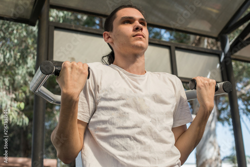 Canvas Print A young man works out in an outdoor gym located in a city park