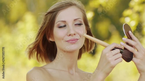 Young beautiful woman puts foundation on face