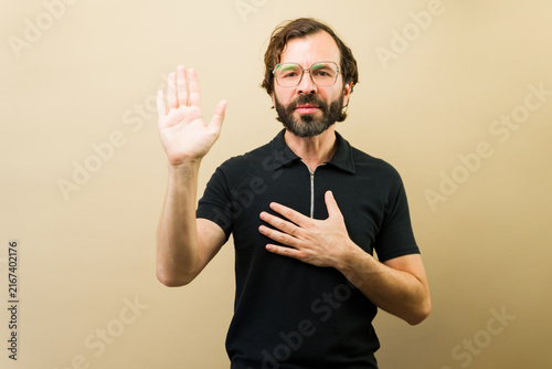 Canvastavla Hispanic man making an oath with hand on chest and raised hand showing loyalty,