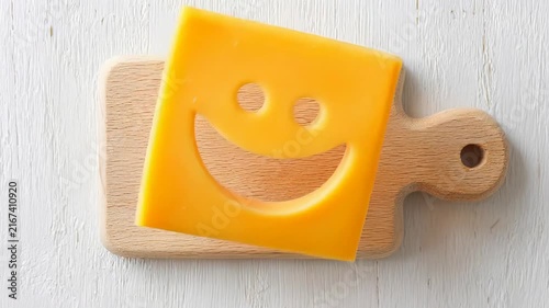 Smiling cheese slice on wooden cutting board with light background