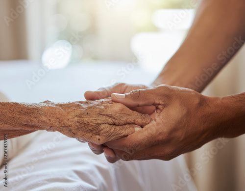 Caregiver hands gently holding wrinkled elderly hands with compassion