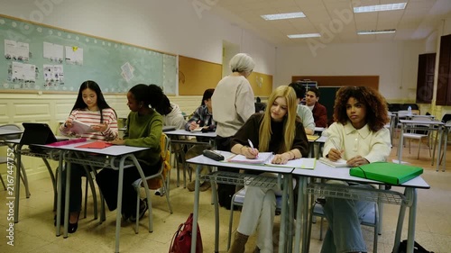 Diverse group of high school students attentively listening to their teacher in a classroom
