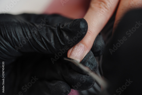 Принти на полотні Close-up of a nail technician filing client nails with an emery board, showcasing cosmetic care and hygiene practices