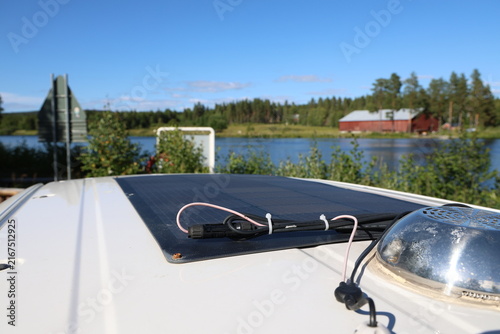 Close-up photo of a flexible solar panel installed on the roof of a white camper van.