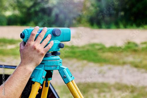 Tripod mounted level supports surveying operations as professional user fine tunes scope position and bubble alignment for precise measurements.