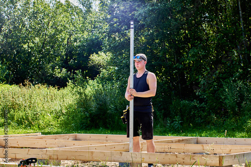Surveyor grips graduated measuring rod firmly while checking position for accurate land measurements and construction site planning.