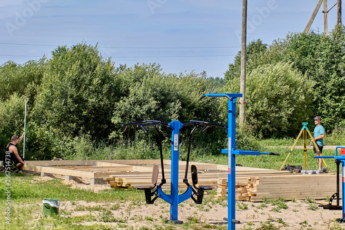 Surveyor operating optical instrument on tripod coordinates with colleague holding leveling rod, ensuring precise measurements at construction site.