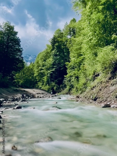 Breathtaking Partnachklamm Gorge in the Bavarian Alps, Germany, featuring dramatic limestone cliffs, crystal-clear rushing water, and lush green vegetation. 