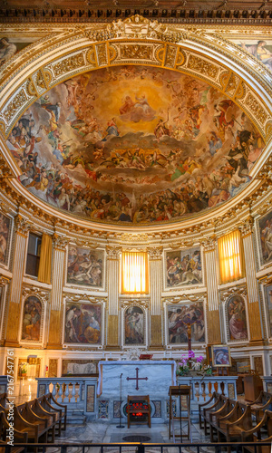 Interior of the Basilica of Santi Quattro Coronati in Rome, Italy, featuring wooden pews and the majestic apse fresco of the Glory of Paradise