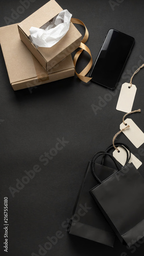 A collection of shopping bags, gift boxes, and a smartphone on a dark surface, evoking the essence of online shopping and commerce.
