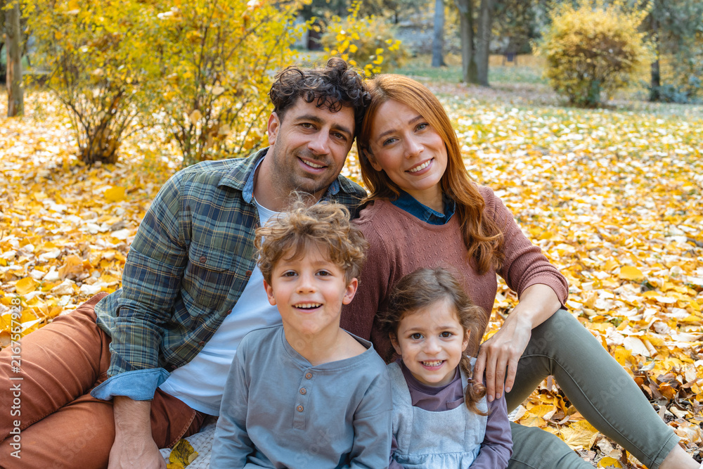 Fototapeta premium Happy family of four enjoying a beautiful autumn day in the park