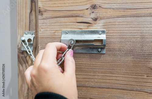 Foto Close up of hand holding security door chain on wooden door