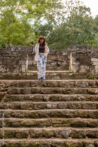 A tourist walking down the steps at some ancient Mayan stone ruins in Yaxhá, Guatemala