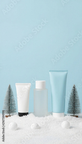 Cosmetic tubes and bottles in artificial snow with pine trees