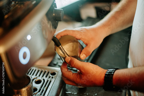 Fotografie Barista preparing espresso at a professional coffee machine, carefully handling the portafilter during the brewing process in a specialty cafe