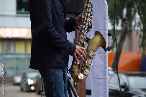 Obraz na plátně A male saxophonist is playing the saxophone on the city street.
