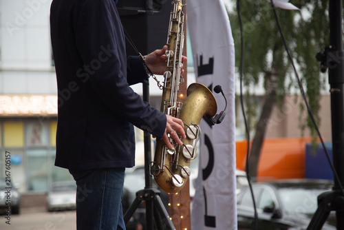 Fotografie A male saxophonist is playing the saxophone on the city street.