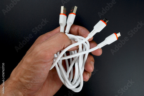 micro USB cables for data transfer and charging in male hands on black background