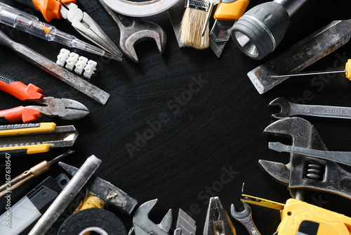 Assorted hand tools arranged around open center on black background