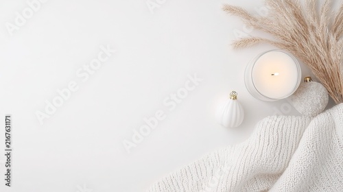 Minimalist New Year background with cozy candle, ornaments and textured knit fabric on white
