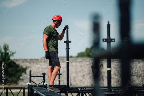 Canvas Print Male worker building a temporary outdoor stage structure for an event, focusing