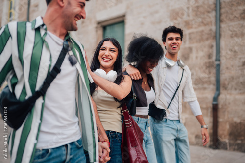 Obraz na plátne Diverse group of young adult friends walking, laughing, and bonding in city stre