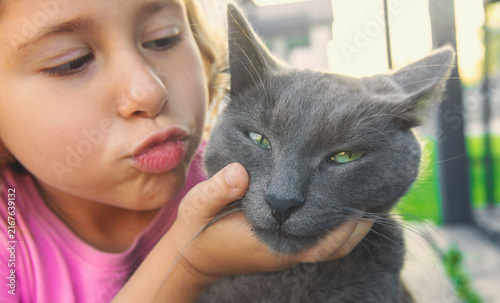 Quadro su tela A child loves a cat outdoors. Selective focus.