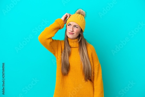 фотографія Young caucasian woman wearing winter jacket isolated on blue background having d