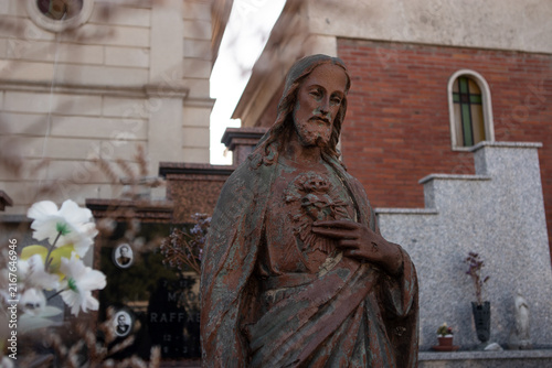 Картината върху платно Statua monumentale del Sacro Cuore di Gesù in un cimitero storico con cappelle g
