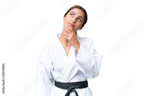 Young Uruguayan woman doing karate over isolated background looking up while smiling