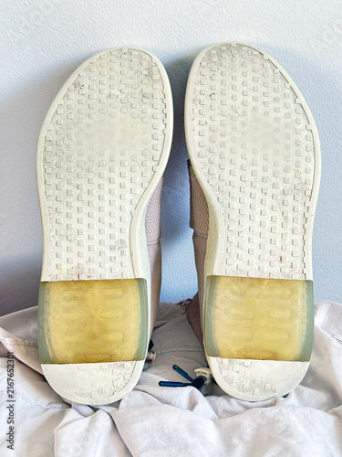 Beige High-Top Canvas Sneakers Viewed from the Back on White Surface. Pair of Blush Pink Sneakers on White Surface. Close-up of Textured Fabric and Leather Material.