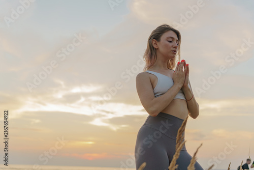 Graceful woman practicing yoga at sunset by the serene ocean, connecting mind and body in a peaceful moment