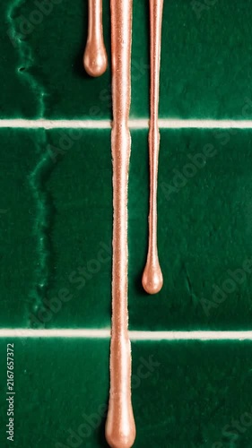 Rose Gold Metallic Liquid Dripping Down Over Textured Dark Emerald Green Tiles for Modern Abstract Backgrounds