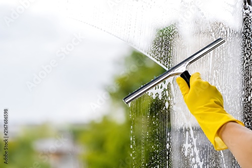 Hand cleaning glass with squeegee outdoors