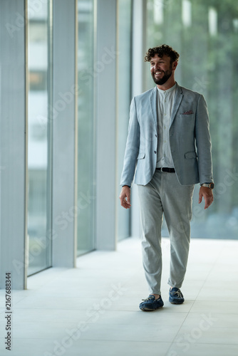 Foto Businessman walking confidently through modern office corridor
