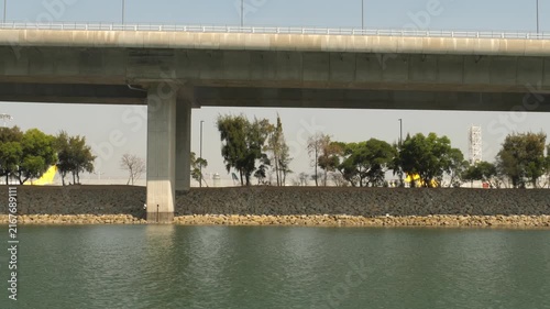 Hong Kong Zhuhai Macao Bridge viaduct over sea water near airport green shoreline with airplane tails visible in background on sunny day, tracking camera movement