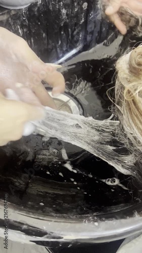 Hairdresser washing woman hair in black sink close up 9:16 vertical, beauty salon concept