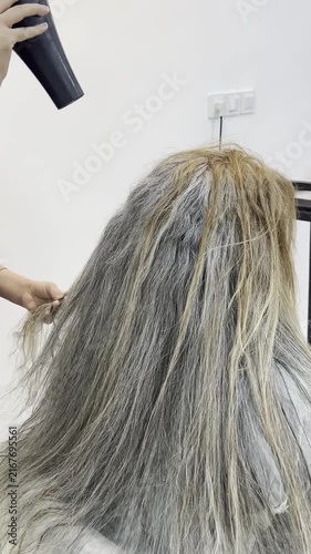 Hairdresser hands drying woman long hair with hairdryer close up 9:16 vertical, beauty salon concept