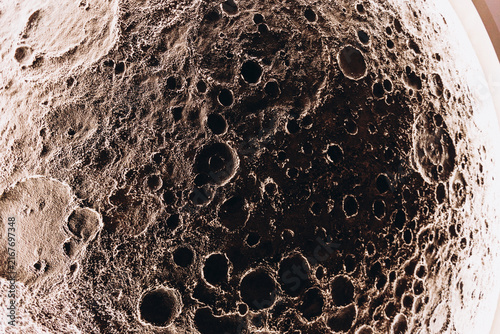 Lunar Surface Detail: A close-up view of the moon's surface reveals a rugged terrain with numerous craters of varying sizes, showcasing the celestial body's ancient and impact-marked history.